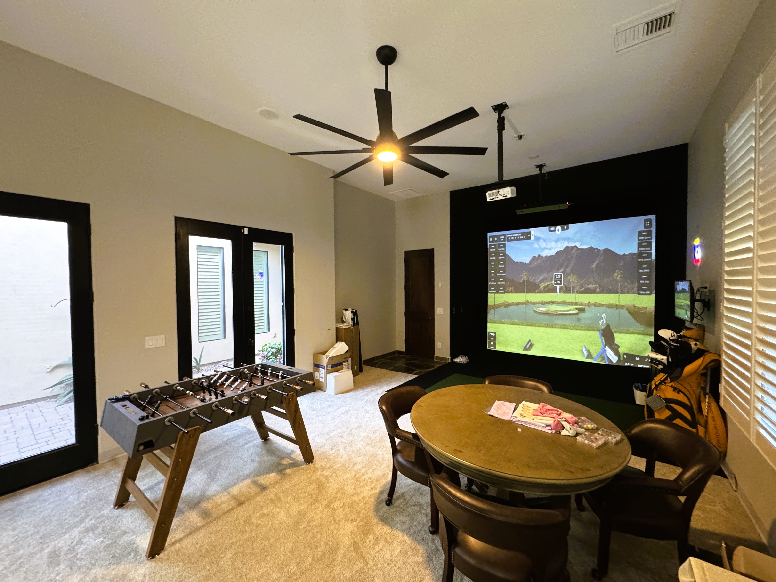 Golf simulator in a bonus room including foosball and game table.