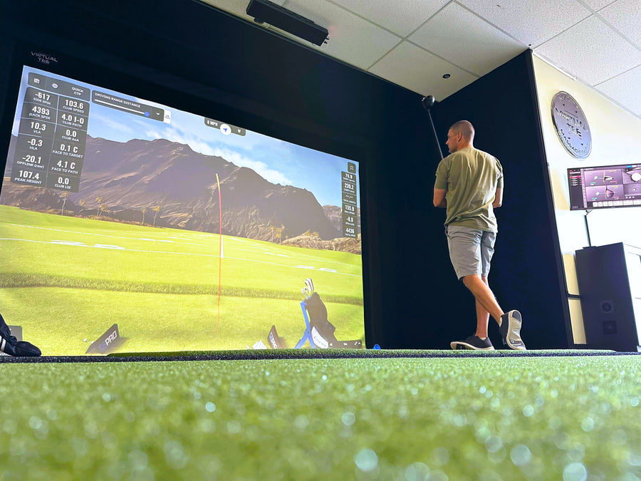 A commercial golf simulator with a man finishing a swing.