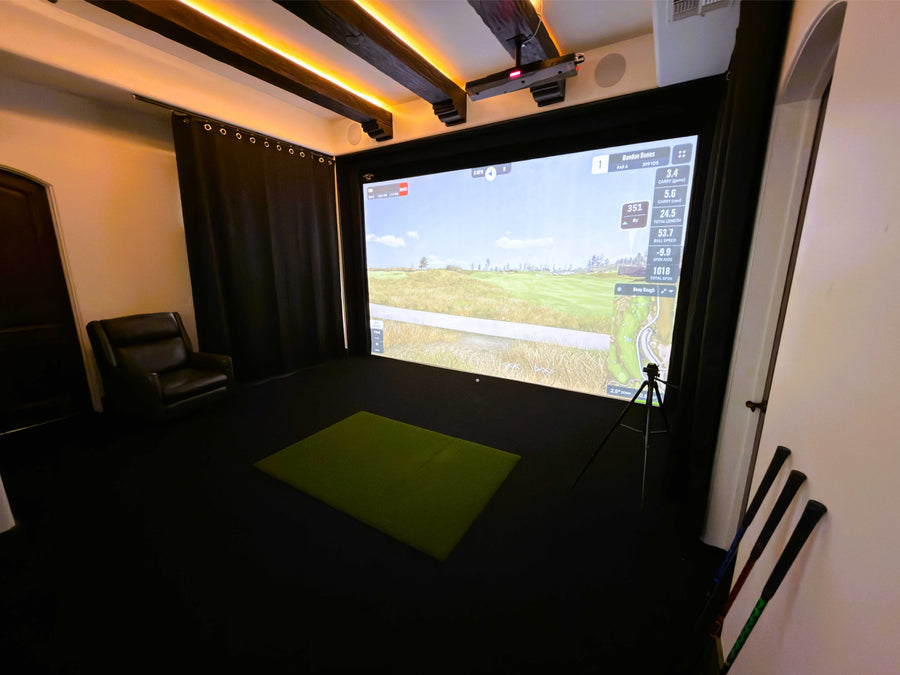 Indoor simulator setup with a screen displaying a virtual environment, surrounded by dark curtains.