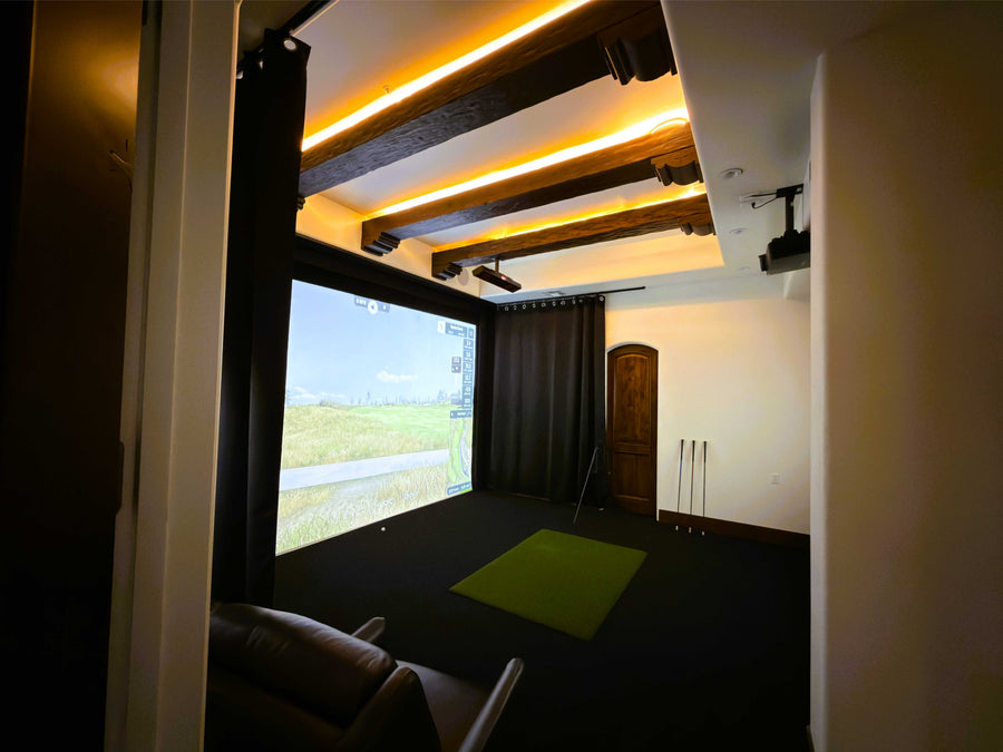 Golf simulator setup with a screen displaying a nature scene, surrounded by dark curtains.