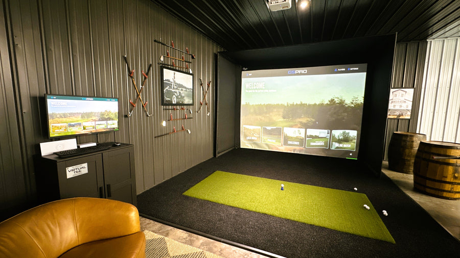 Golf simulator setup in a room with a green mat and TV screens.