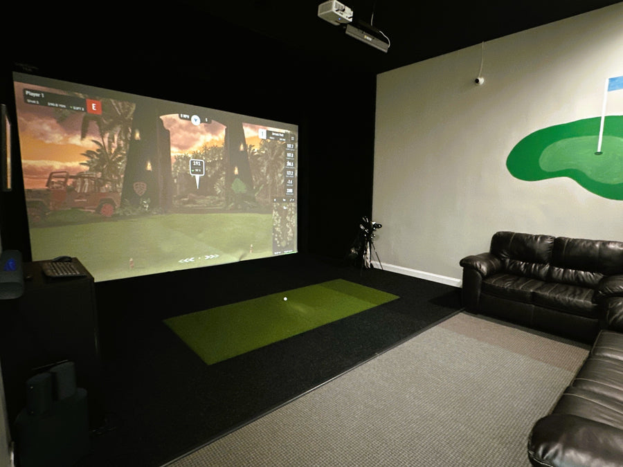 Indoor golf simulator setup in a room with a screen displaying a golf game.