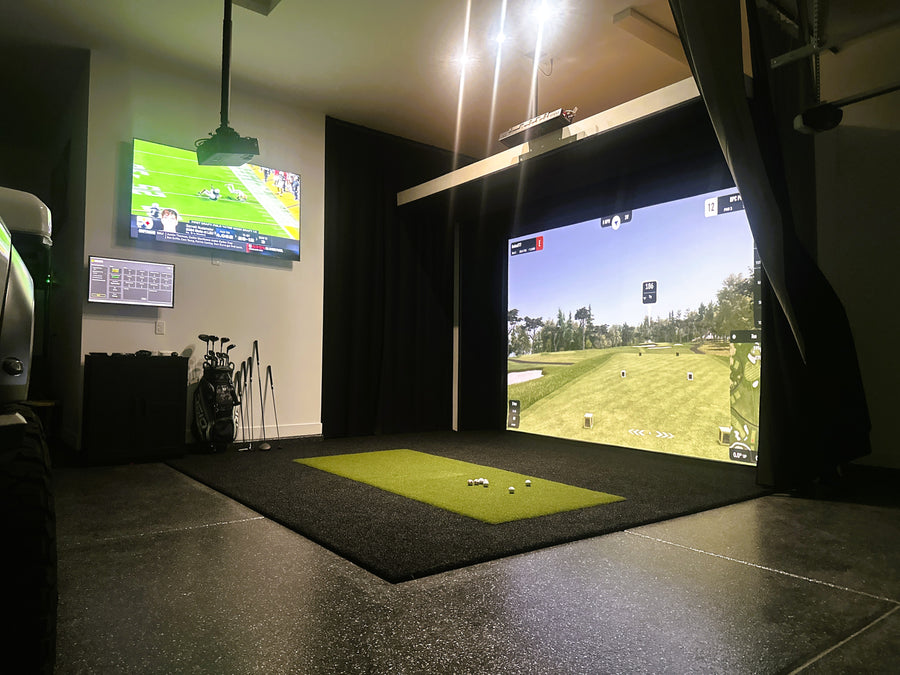 Indoor golf simulator setup with two screens displaying golf games.