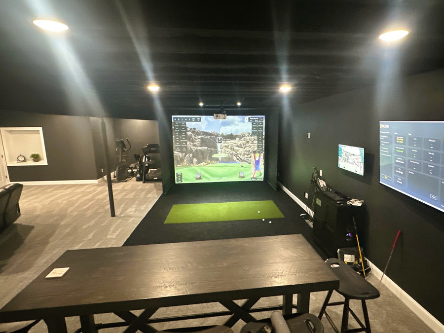 Indoor golf simulator setup with multiple screens in a room.
