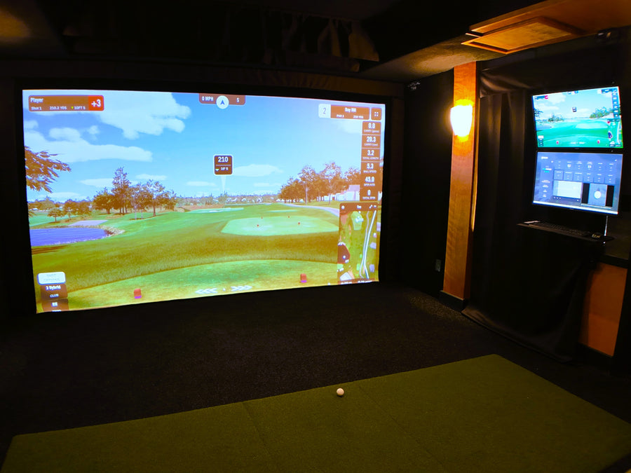 Indoor golf simulator setup with two screens displaying a golf course.
