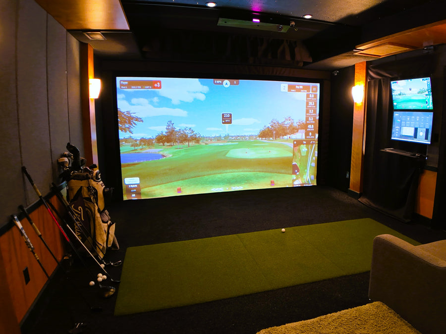 Indoor golf simulator setup with large screen displaying a golf course.