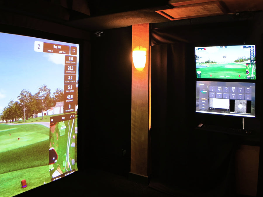 Golf simulator setup with two screens displaying a golf course.