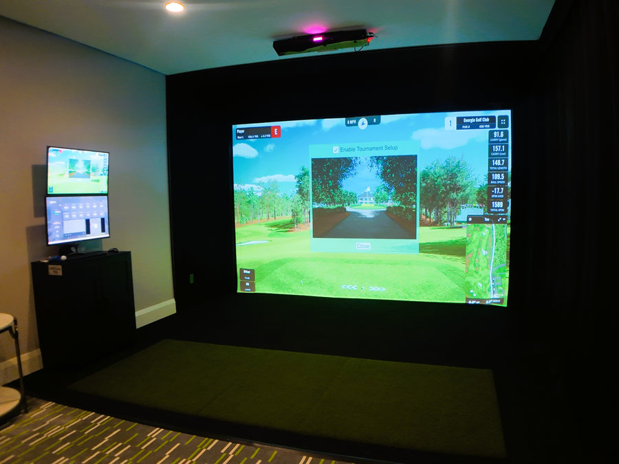 Golf simulator setup with two screens in a room.