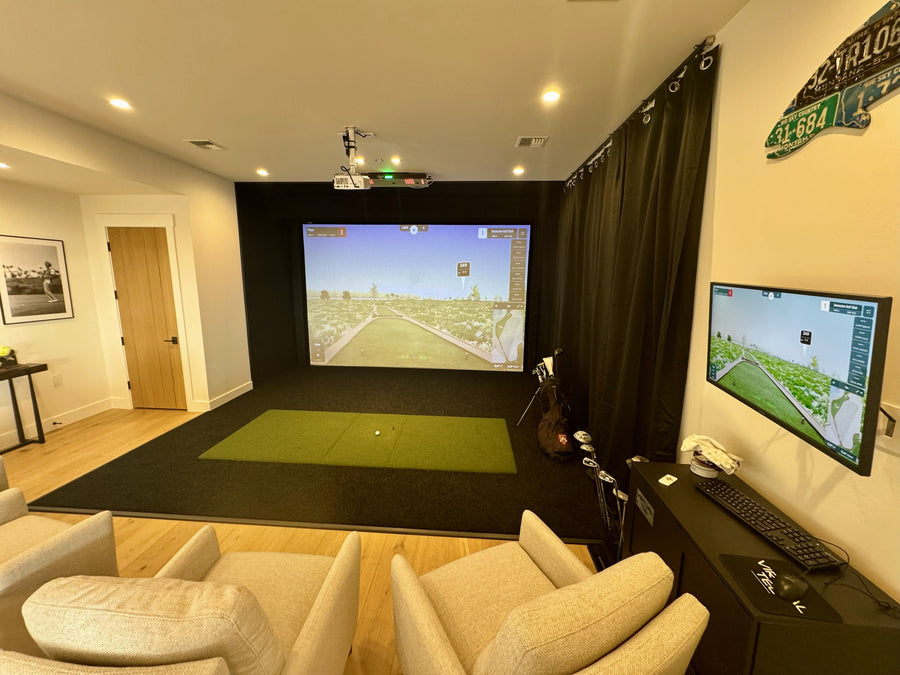 Golf simulator setup in a living room with a large screen and additional monitor.