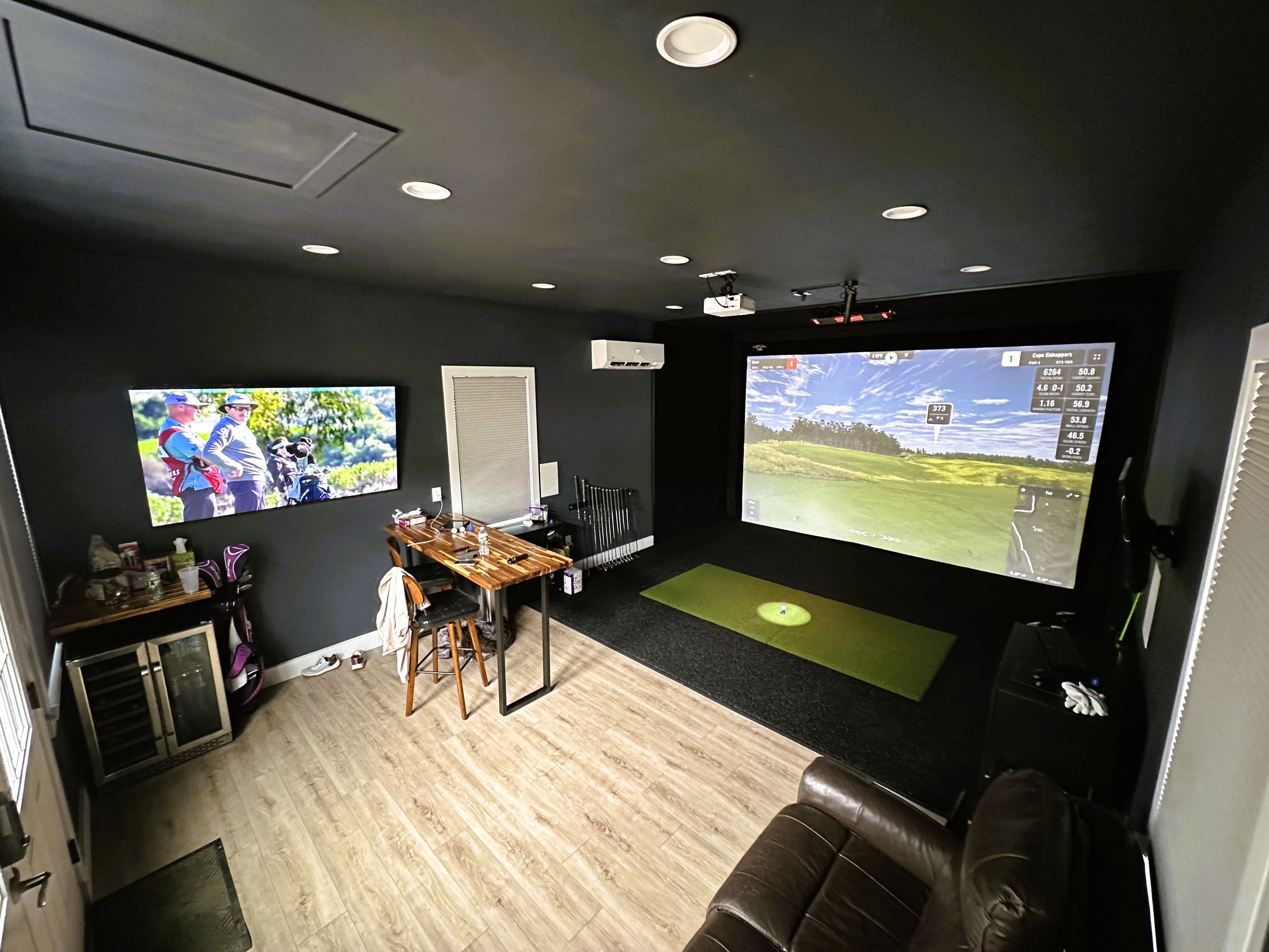Outbuilding golf simulator with large screen, black turf, and green hitting mat in Hopedale, MA