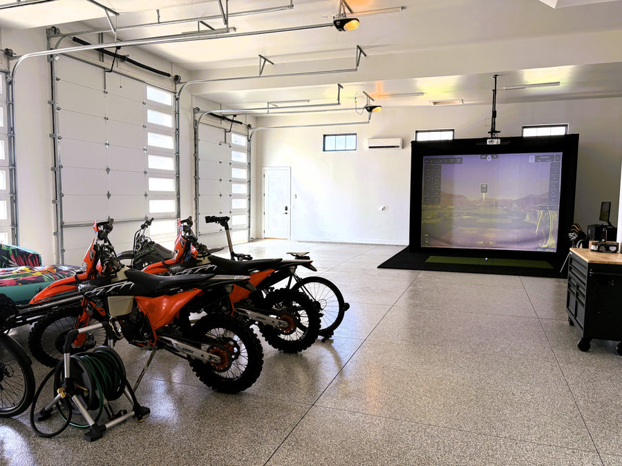 Garage with dirt bikes and a golf simulator screen displaying a game.