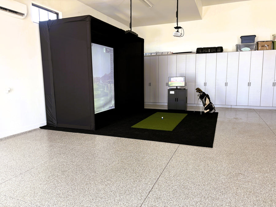 Indoor golf simulator setup in a garage with a screen and golf mat.