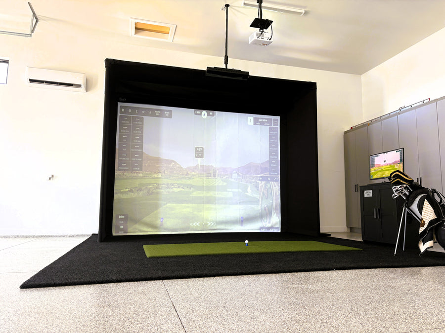 Indoor golf simulator setup in a room with a screen displaying a golf course.