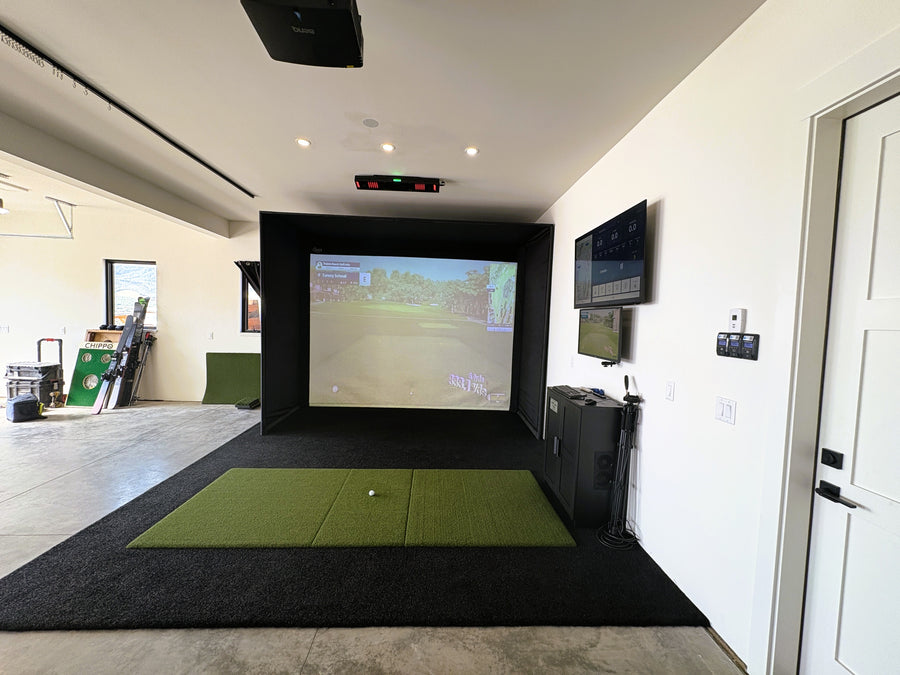 Indoor golf simulator setup in a home with a screen displaying a golf course.