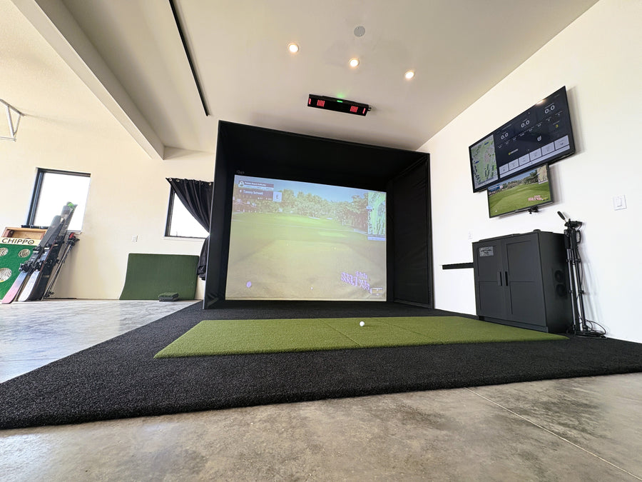 Indoor golf simulator setup with screen and equipment in a room.
