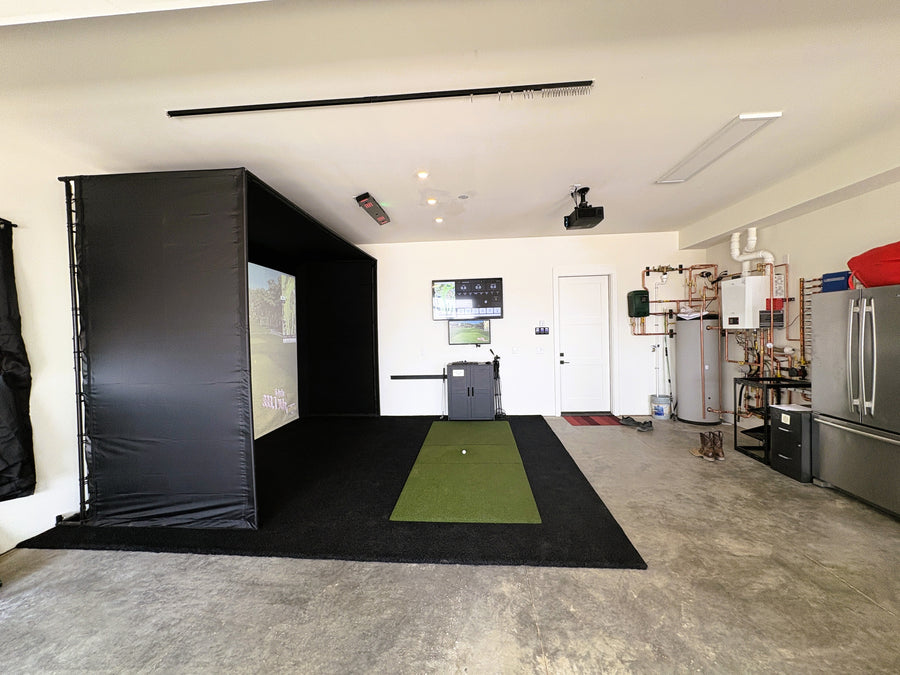 Indoor golf simulator setup in a home garage with a screen and projector.
