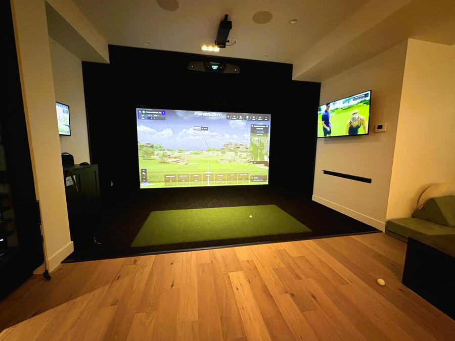 Indoor golf simulator setup with multiple screens in a room.