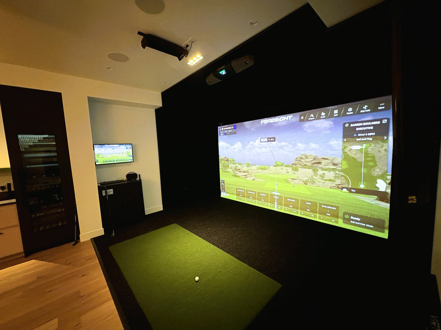 Indoor golf simulator setup with large screen displaying a golf course.