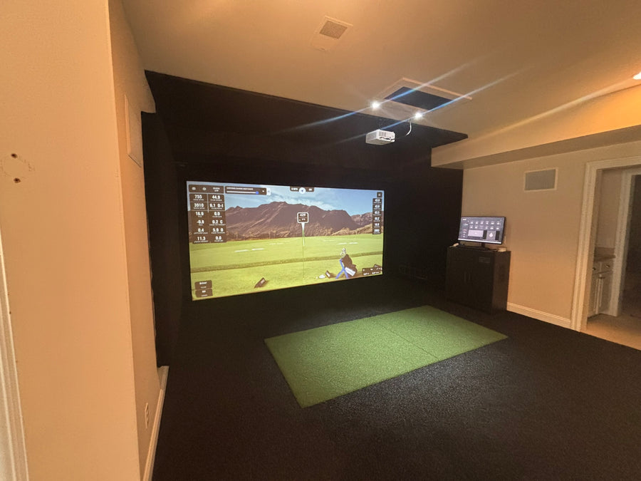 Indoor golf simulator setup with a screen displaying a golf course.