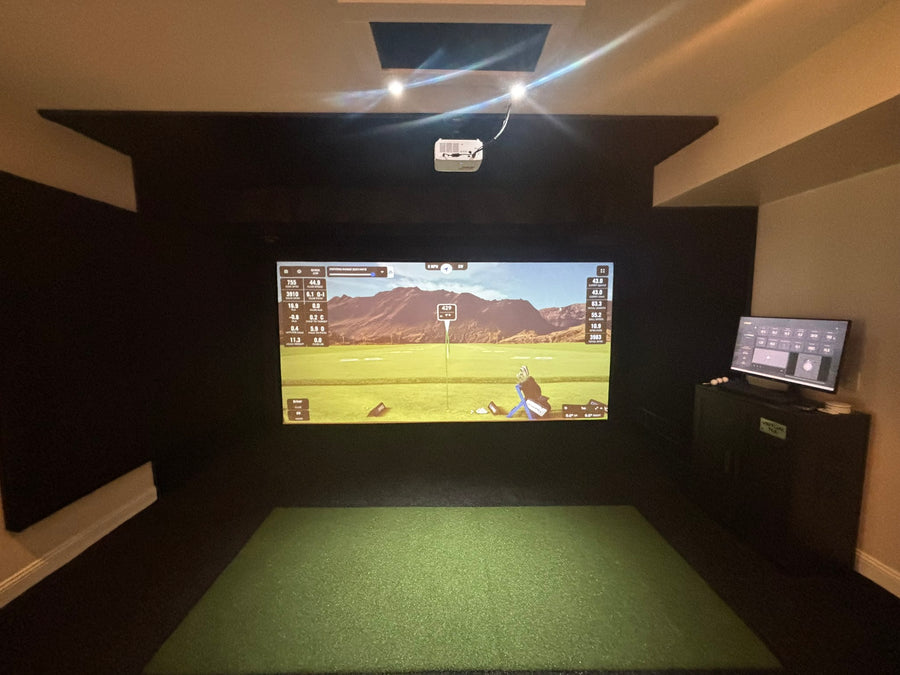 Indoor golf simulator setup with screen displaying a golf game.