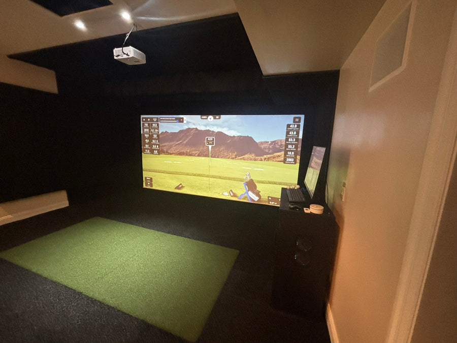 Indoor golf simulator setup with screen displaying a golf course.