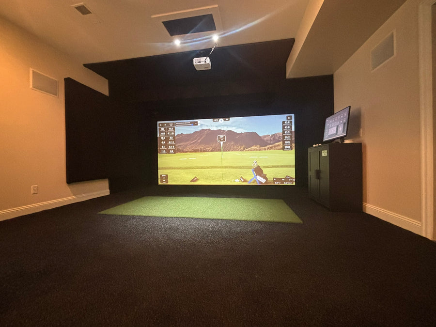 Indoor golf simulator setup with two screens in a room.