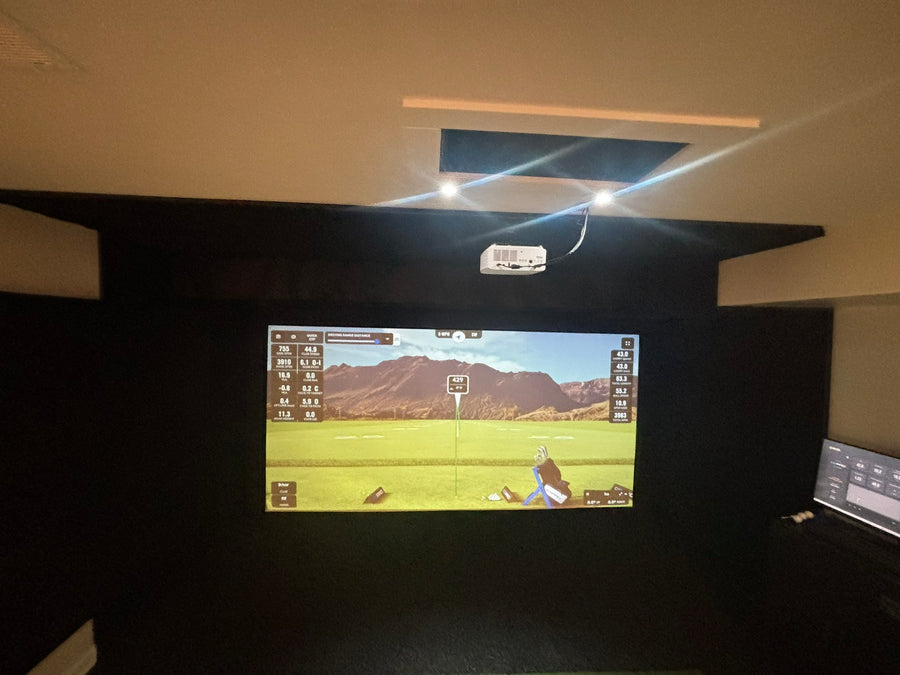 Golf simulator setup with screen displaying a golf course on a dark background