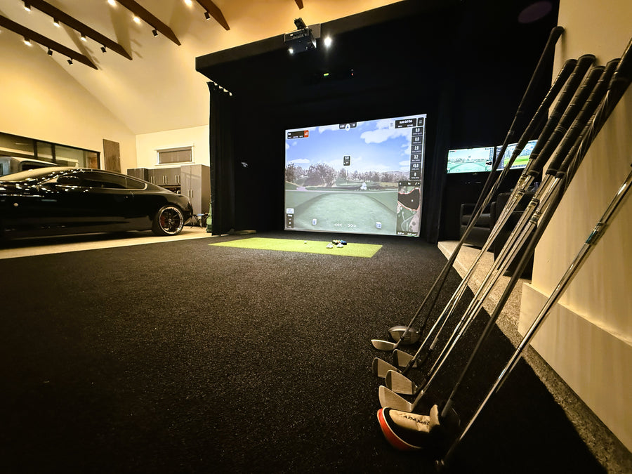 Indoor golf simulator setup with golf clubs and a car in the background