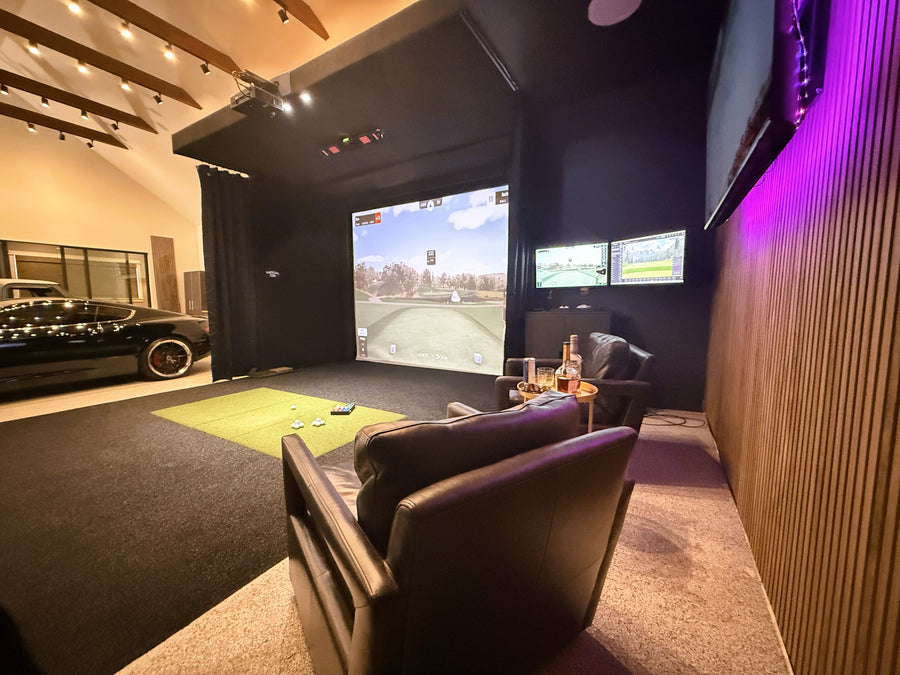 Modern golf simulator with large screen displaying a game, surrounded by comfortable seating and ambient lighting.