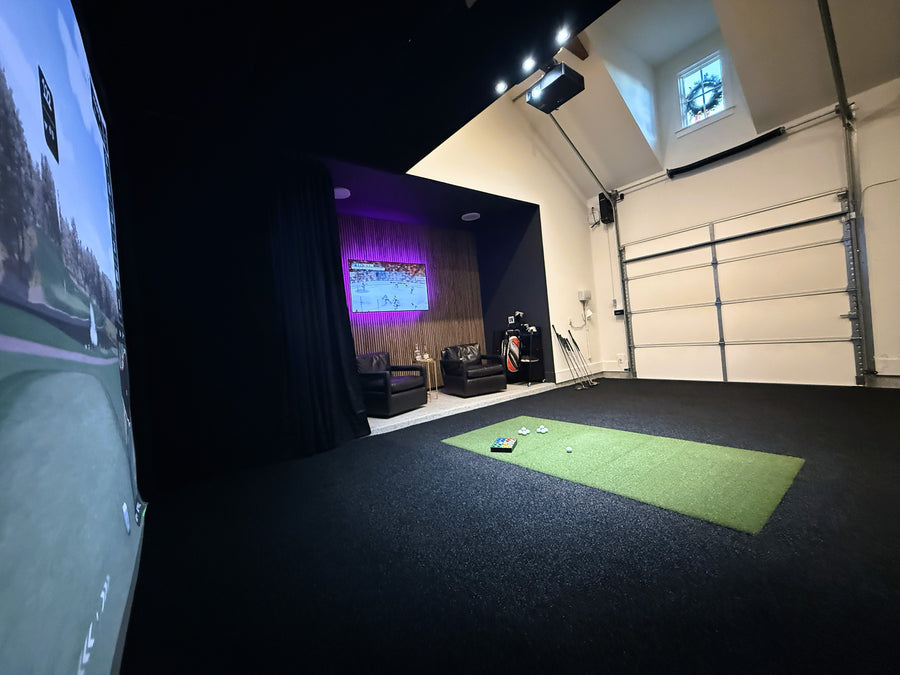 Indoor golf simulator setup in a room with a green mat on the floor.