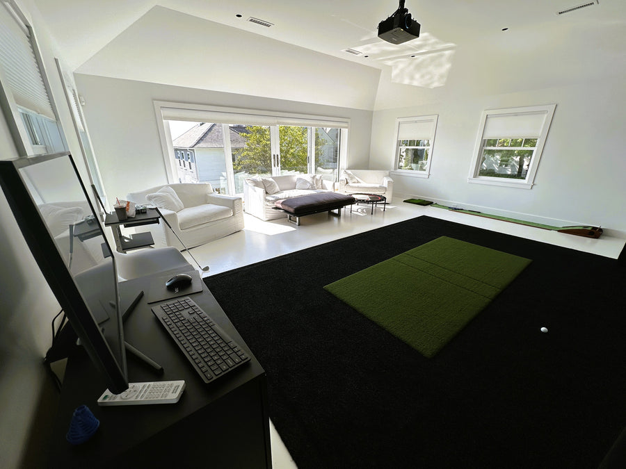 Indoor golf simulator, computer setup, and a living room in the background.