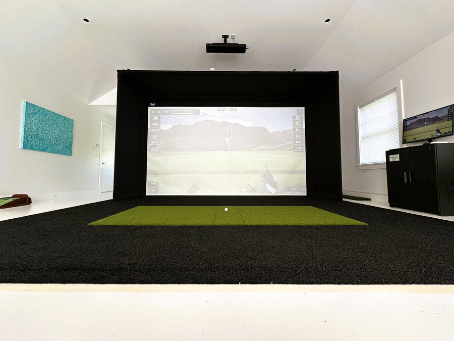 Indoor golf simulator setup with screen and projector in a room.