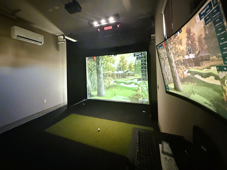 Golf simulator setup with two screens displaying a golf course.