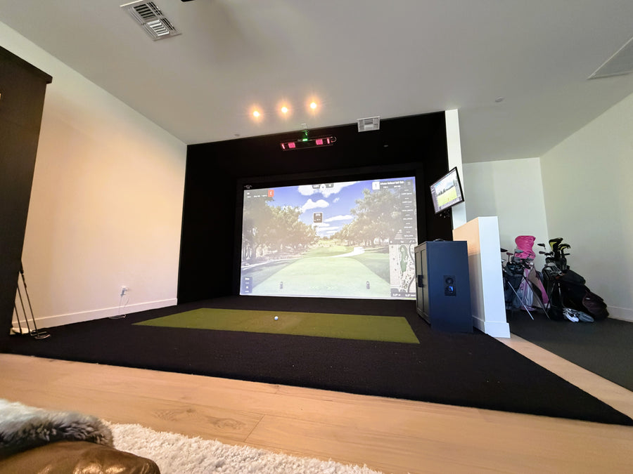 Indoor golf simulator setup with a screen displaying a golf scene.
