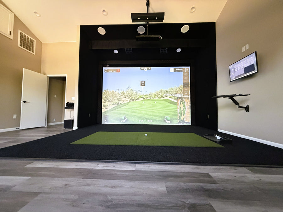 Indoor golf simulator setup in a room with a screen displaying a golf course.