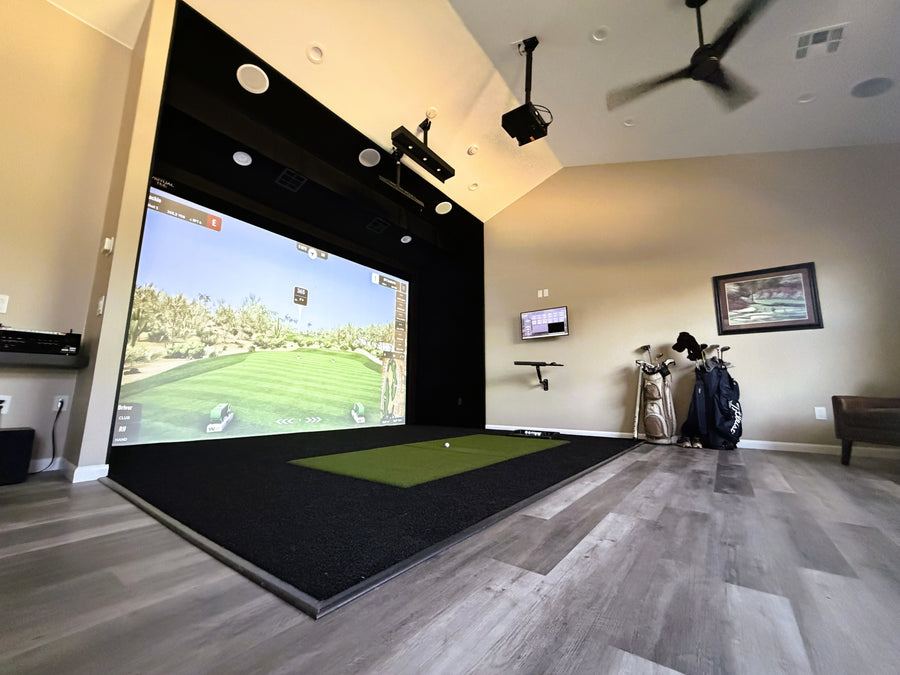 Golf simulator setup in a home room with a large screen and golf equipment.