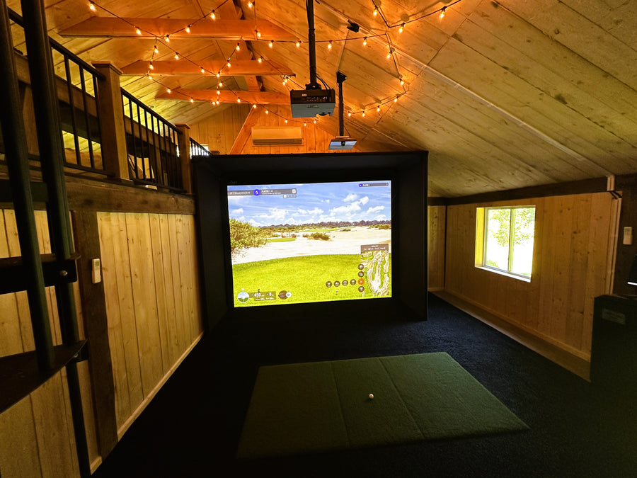 Barn golf simulator setup in a room with wooden walls and ceiling.
