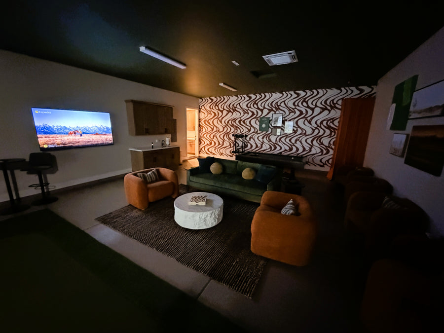 Living room with a TV, sofa, and decorative items in a golf simulator room.