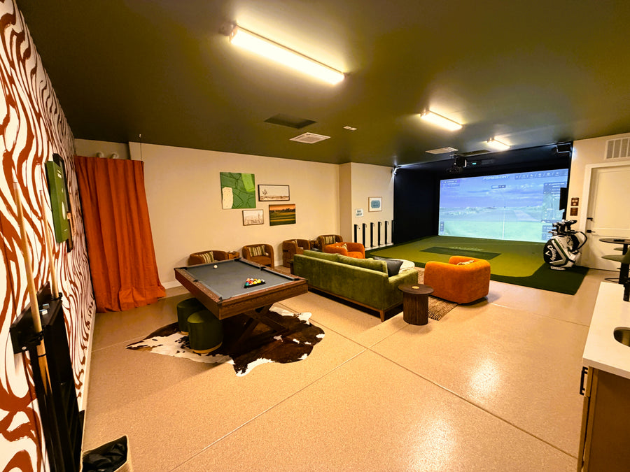 Game room with pool table, couch, and golf simulator setup.