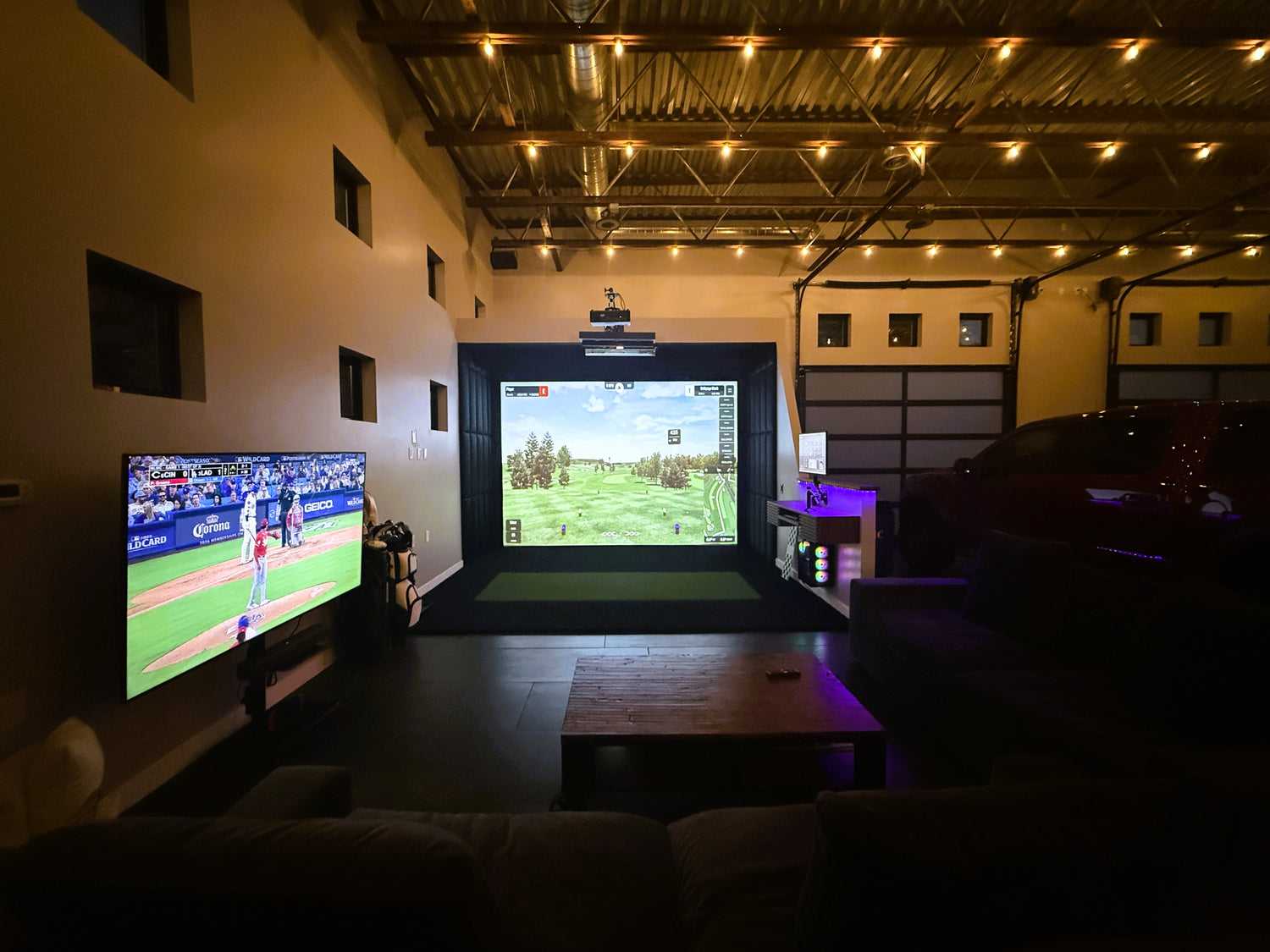 Indoor golf simulator setup with two screens displaying different sports games.