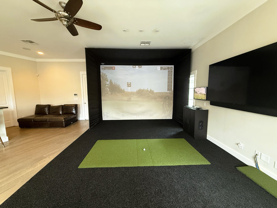 Indoor golf simulator setup in a living room with a screen displaying a golf course.