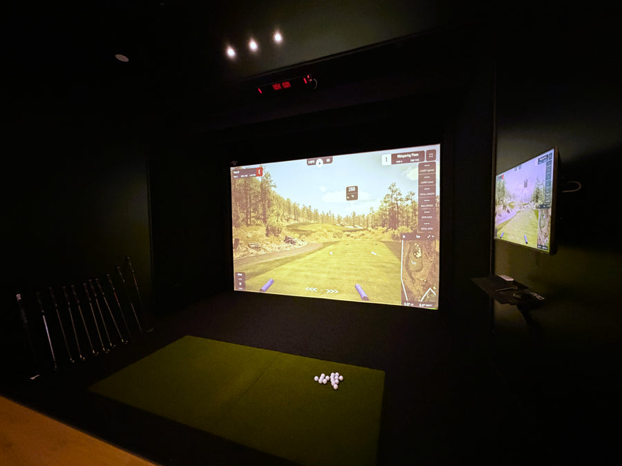 indoor golf simulator in a dark room displaying gspro software.