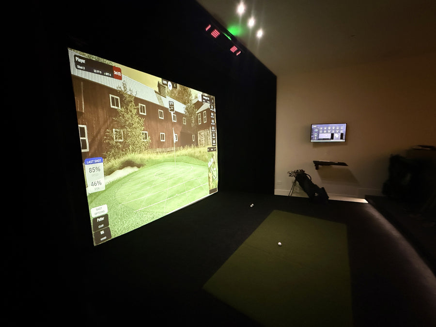 Indoor golf simulator setup with screen displaying a virtual golf course.