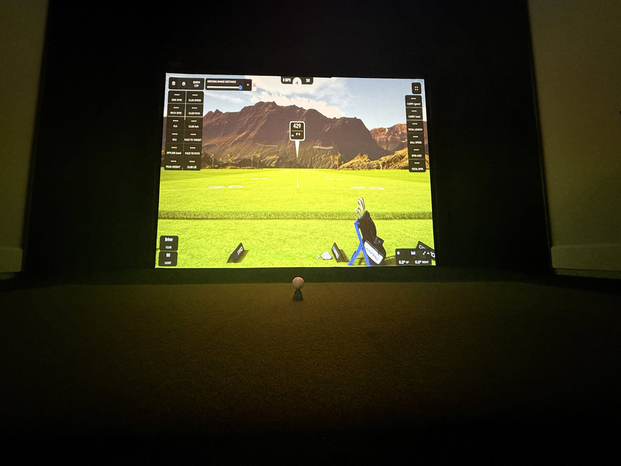 Golf simulator setup with screen displaying a golf course and a golfer's virtual image.