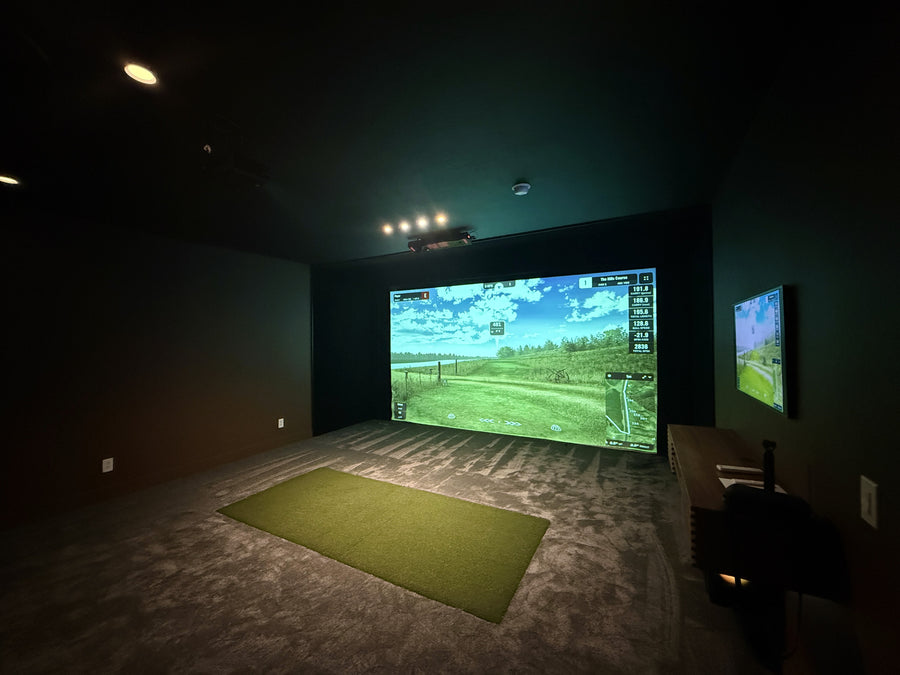 Indoor golf simulator setup with two screens in a dark room
