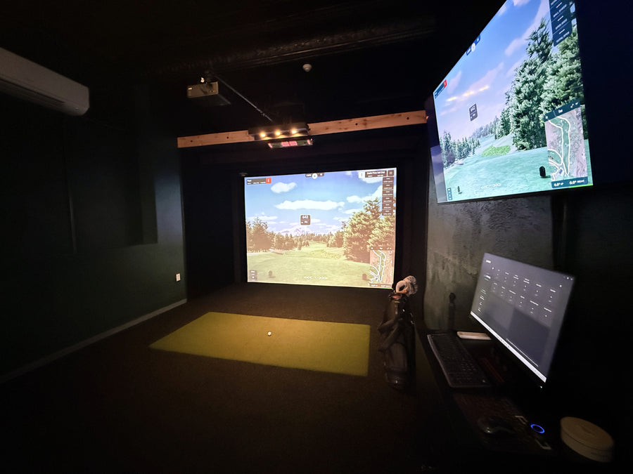 Indoor golf simulator setup with two screens displaying a golf course.