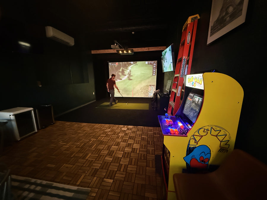 Arcade game in a dimly lit room with a golf simulator.