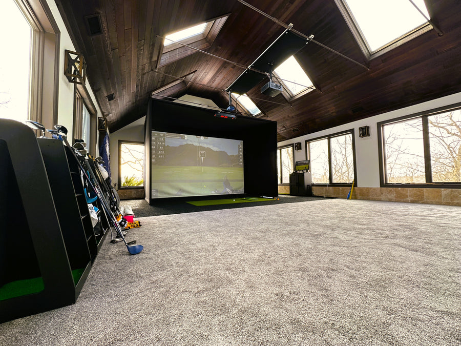 Indoor golf simulator setup in a room with large windows.
