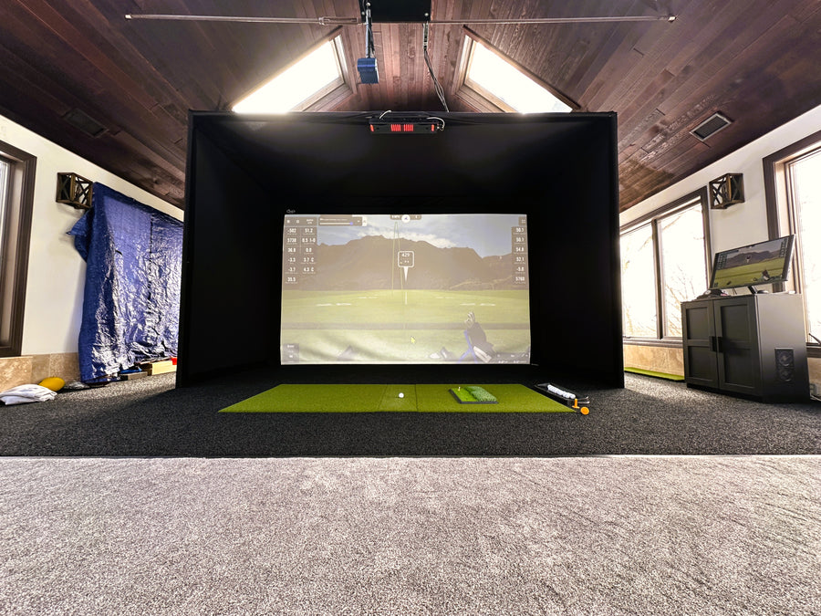 Indoor golf simulator setup in a room with a large screen displaying a golf course.