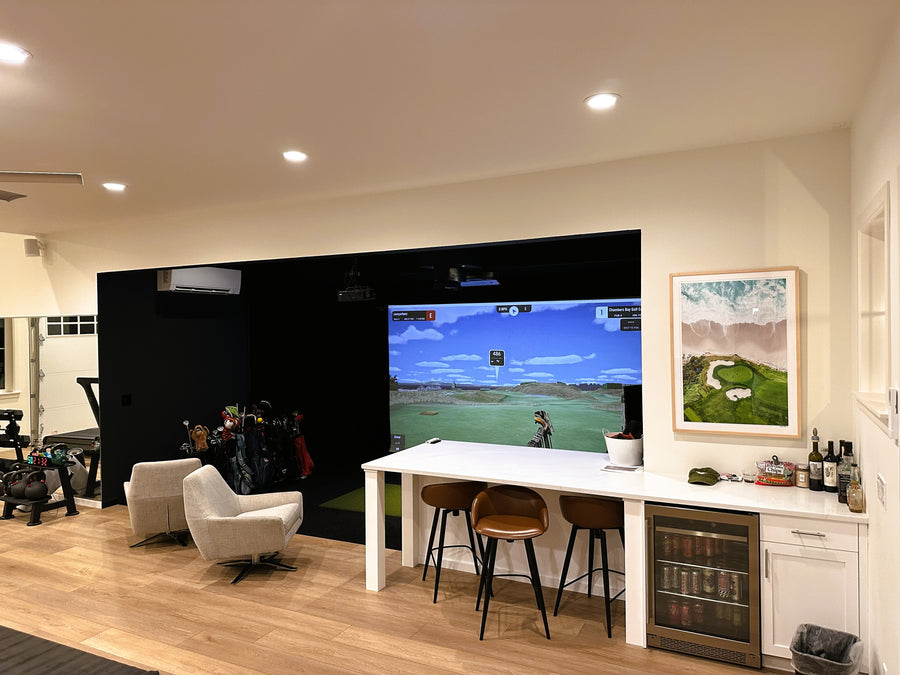 Golf simulator room inside garage with lounge area. 